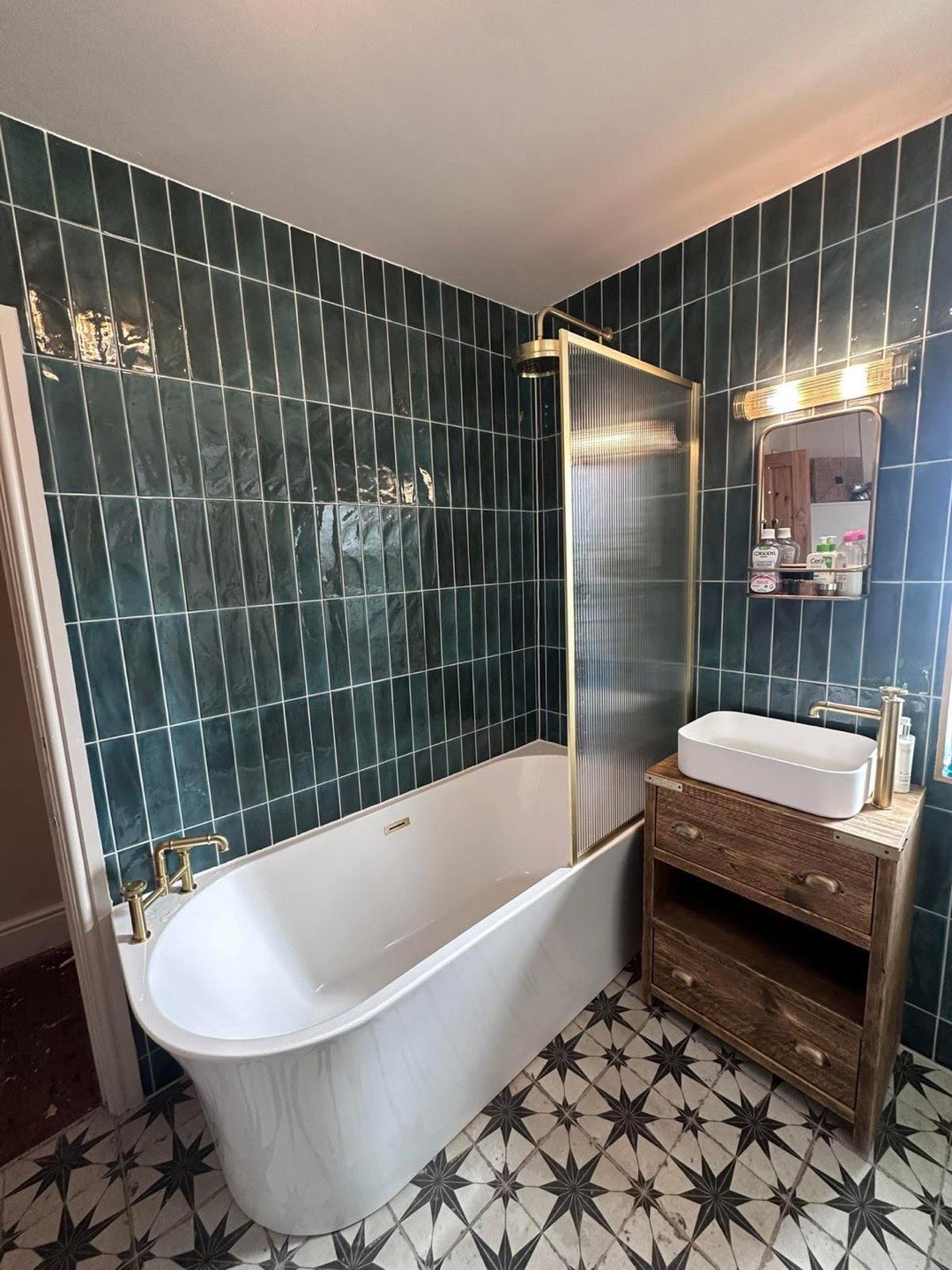 Bathroom with emerald metro tiles, freestanding bath, brass fittings and patterned floor