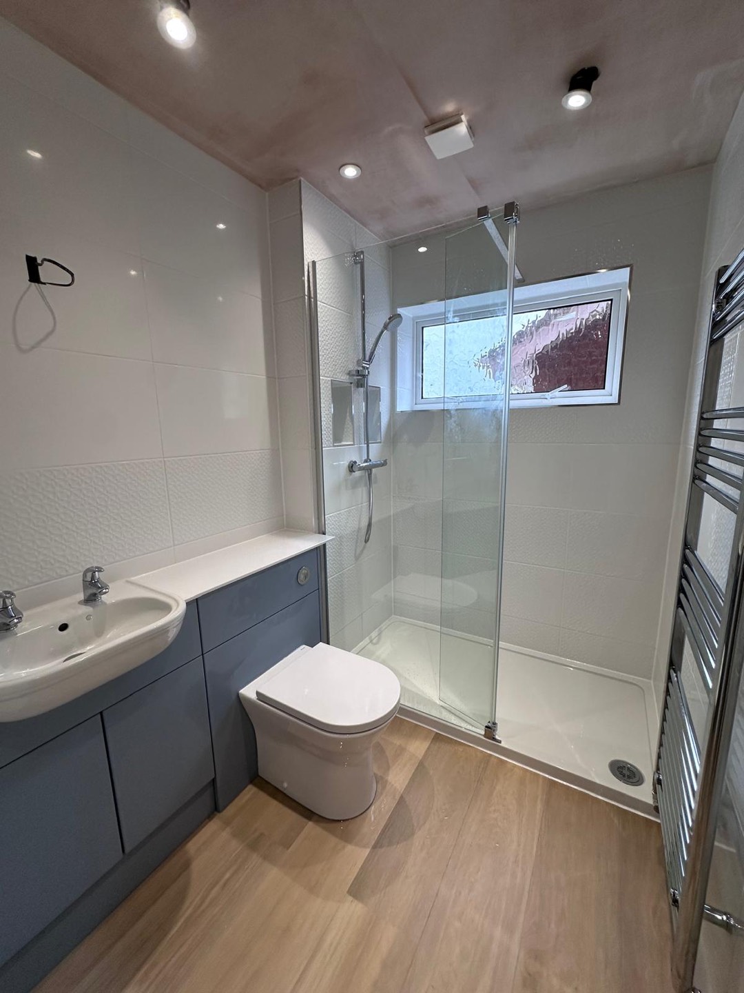 Bathroom with walk-in shower enclosure, glass screen, grey vanity unit and wood-effect flooring