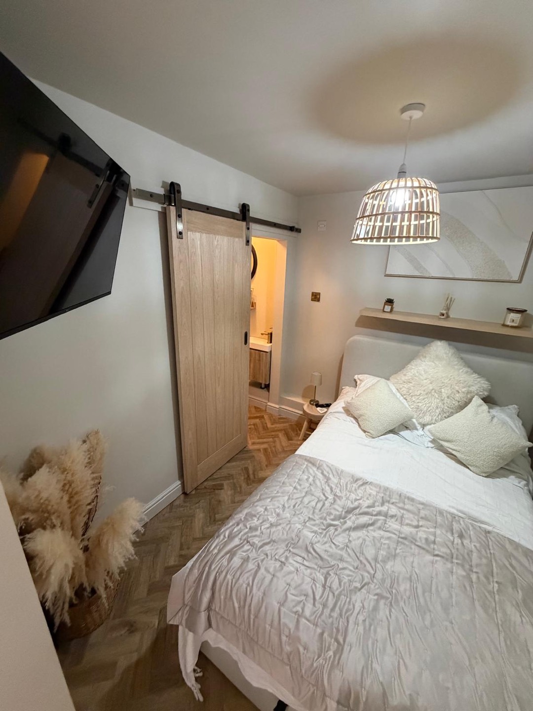 Bedroom with oak sliding barn door, herringbone flooring and ensuite beyond